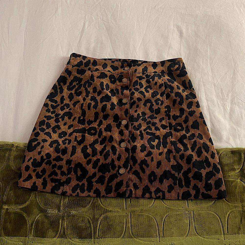 Alaiv Leopard Print Mini Skirt with metal snap buttons down the front.